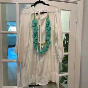 White sundress with open back and beaded pom-pom embellishments.